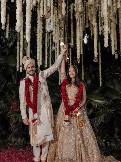 The triumphant "just married" pose under a ceiling of hanging tuberoses. The joy on their faces says it all.