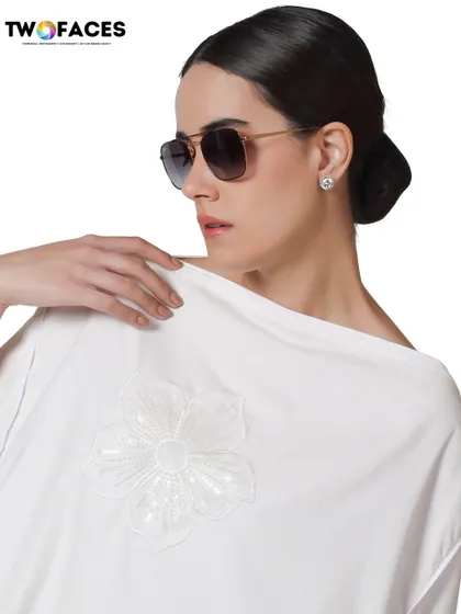 A model wearing a white kaftan-style top with sunglasses, exuding a relaxed yet glamorous vibe for a resort or vacation wear collection.