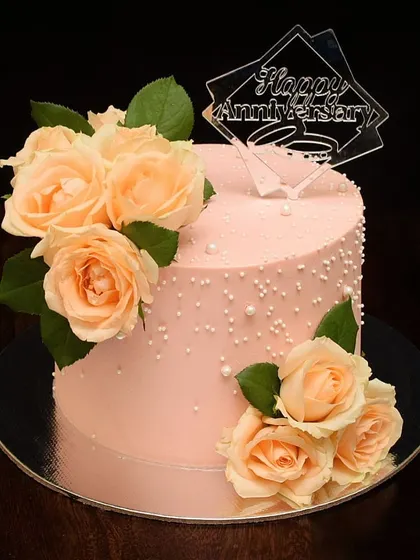 A beautiful anniversary cake in a lovely peach color. This design is adorned with fresh peach roses and a custom acrylic "Happy Anniversary" topper, making it a simple yet stunning centerpiece.