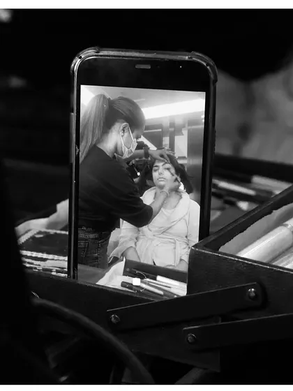 An artistic shot of our makeup artist at work, viewed through a phone screen. This image creatively captures the essence of our on-the-go, modern service.
