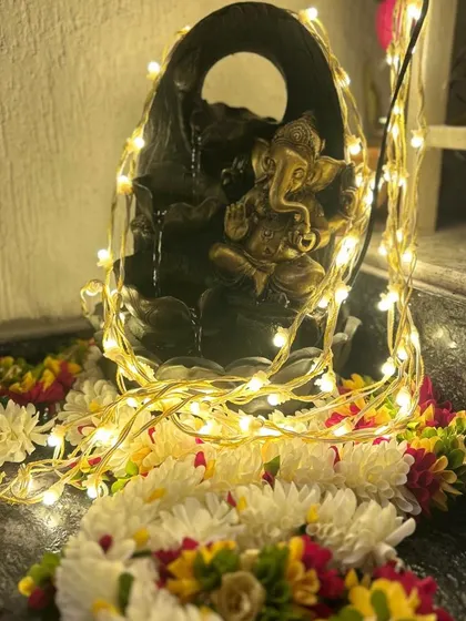 Every corner counts when celebrating a new home. We created this serene little nook with a Ganesha water fountain, fairy lights, and fresh flower garlands for an auspicious touch.