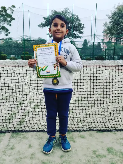 Manit Shokeen proudly displaying his bronze medals for both the U-10 and U-8 categories. His dedication on the court led to this fantastic achievement in the Tennisoholic tournament.