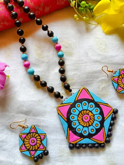 A hexagonal pendant necklace with a vibrant mandala design in pink and blue. This geometric shape gives a modern edge to the traditional art form.
