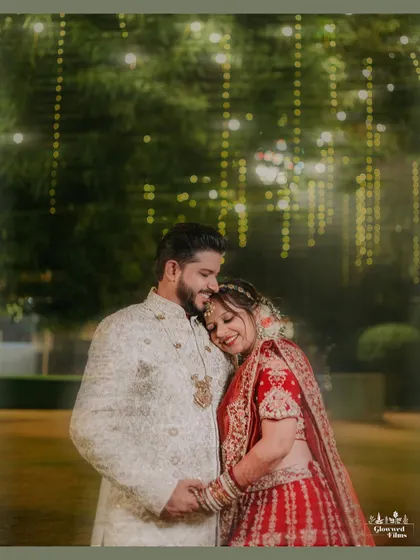 A cozy and romantic portrait of Vidhi and Vidhan, with the bride resting her head on the groom's shoulder under soft, twinkling lights.