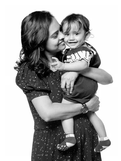 A classic black and white portrait of a mother holding her smiling baby. The simplicity of the shot emphasizes the emotional connection and the baby's adorable expression.