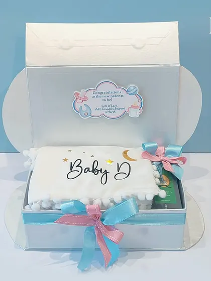 The beautiful packaging for the 'Touch of Heaven' hamper. The clear lid with a custom congratulations sticker allows a peek at the thoughtful gifts inside, building excitement from the first look.