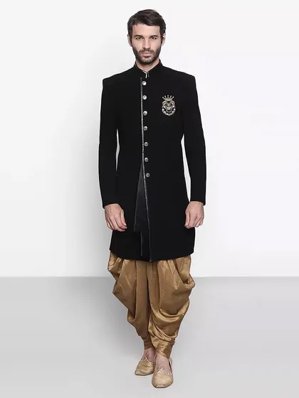 A classic black sherwani-style bandhgala with an embroidered crest, paired with a golden dhoti for a regal look.