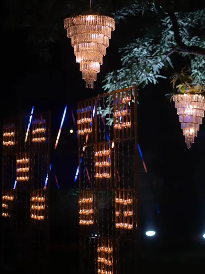 A beautiful night shot of the Diwali decor, featuring tiered chandeliers and intricate candle wall installations that light up the garden.