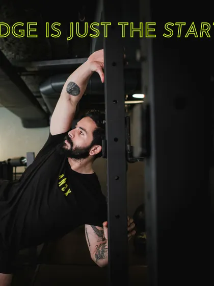 A coach stretches against a power rack. For us, knowledge is just the start; it's the application and dedication that create results.