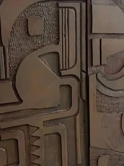 A close-up where two of the wooden panels meet, showing the continuous flow of the abstract design across the separate pieces.
