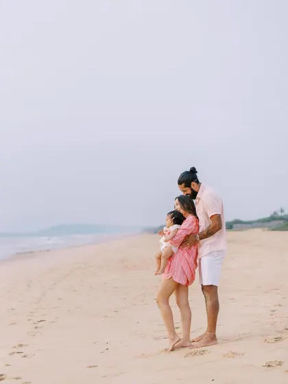 A family standing on the beach, looking out at the ocean. A serene and beautiful portrait.