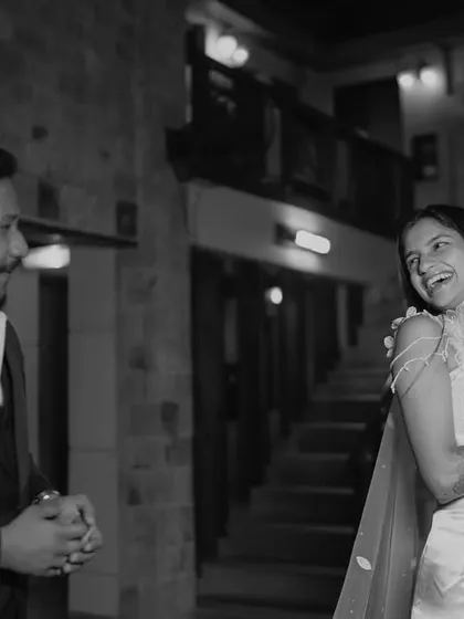 A black and white shot of the couple sharing a laugh during their reception. It's a simple, authentic moment of connection.