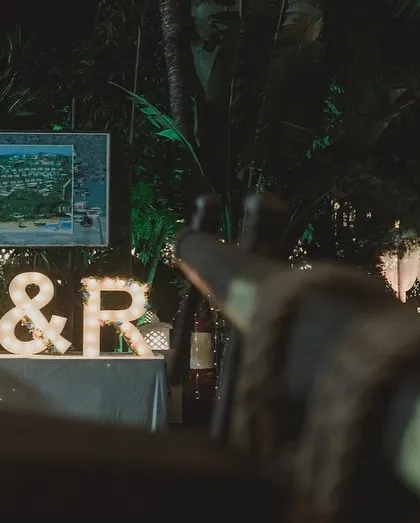 The couple's initials, lit up at night, become a beacon for the celebration. This shows how personalized elements can also serve as landmarks within a large venue.