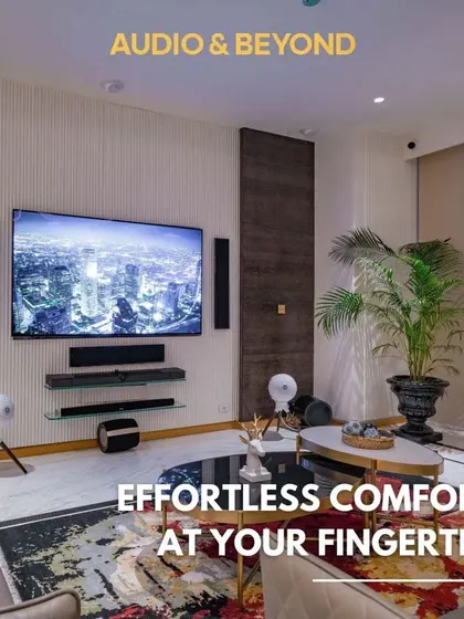 Effortless comfort at your fingertips. This living room showcases a complete audio-visual setup with a large screen and multiple speakers, all of which can be controlled through a single smart home interface for a seamless user experience.