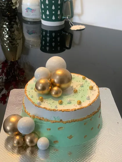 A chic mint green cake decorated with gold and white chocolate ball clusters. The touch of gold leaf adds a bit of luxury.