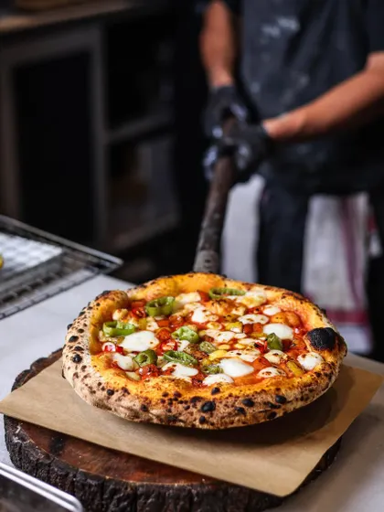 A festive-looking pizza, hot out of the oven. The bright colors of the peppers and cheese make it perfect for any celebration or just a Tuesday night treat.