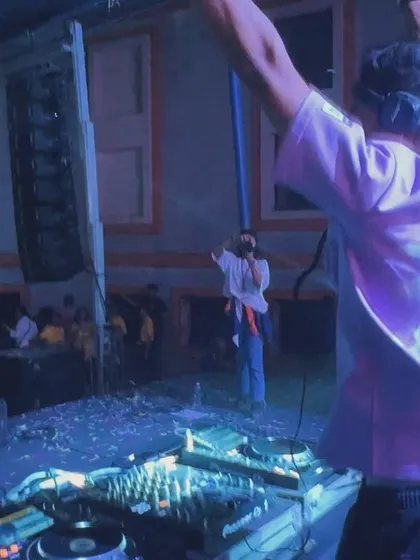 A view from behind the decks at the Mount Carmel College event, with my hands up, feeling the energy from the students.