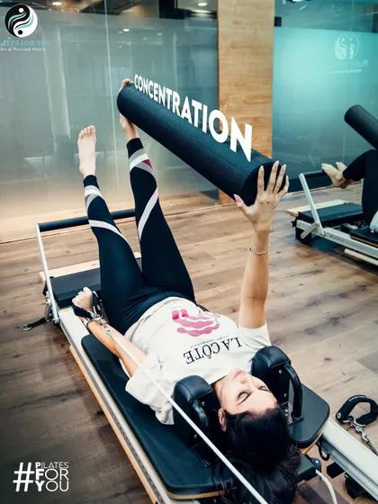 This client holds a challenging pose, demonstrating the concentration and core control that are fundamental principles of the Pilates method.