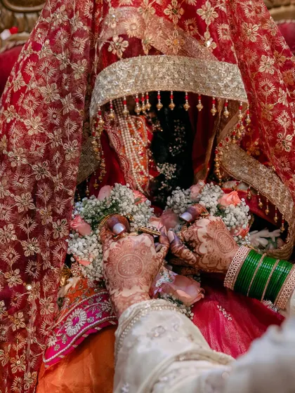 A moment during the ceremony where hands are exchanged. This photo is rich with detail, from the henna to the bride's green bangles and traditional garments.