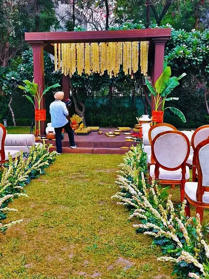 Another perspective of the outdoor puja mandap, showing how the seating is arranged to give every guest a clear view. The combination of natural wood, green grass, and traditional flowers creates a timeless and sacred atmosphere.