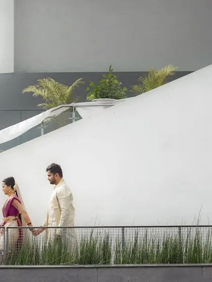 I love using architectural lines to frame my subjects. Here, the couple walks along a modern exterior, their traditional attire creating a beautiful contrast with the clean, white walls.