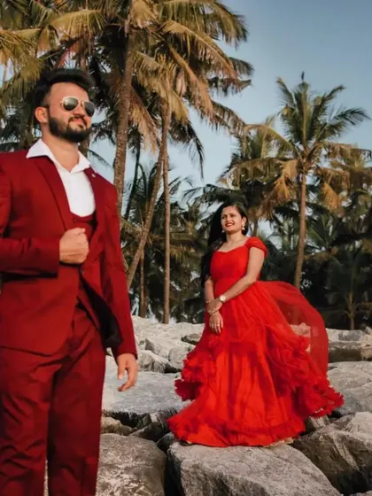This stylish pre-wedding shot on the rocks has a high-fashion feel. The matching red suit and gown look incredibly chic against the backdrop of palm trees.