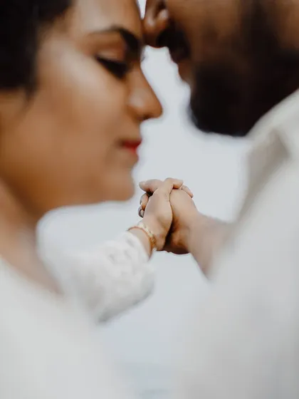 A soft-focus, artistic close-up of a couple holding hands, their faces close together. This shot highlights the small, tender gestures that define a relationship.