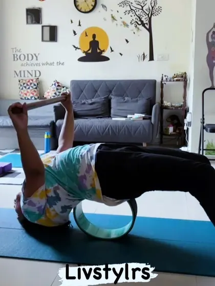 A client uses a yoga wheel to support a deep backbend. This prop is excellent for increasing spinal flexibility and releasing tension in the back and shoulders.