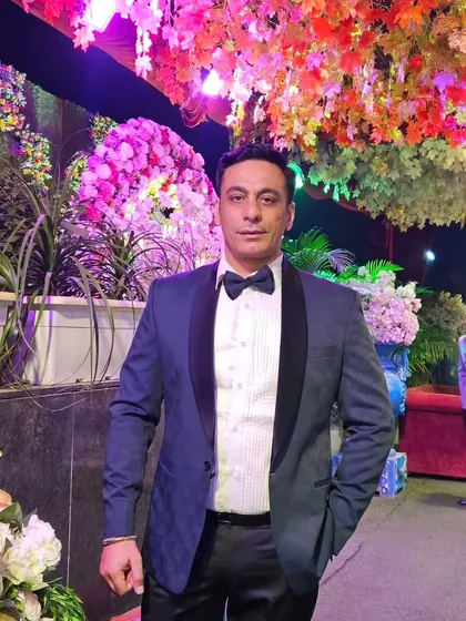 The owner himself in a stylish blue textured blazer with a black lapel, perfect for a wedding event.