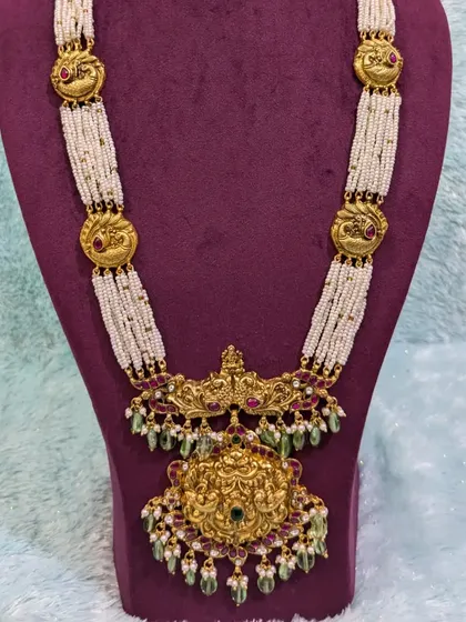 This classic statement haara features a large antique-finish pendant with a touch of Jadau, strung on micro pearl chains. A beautiful fusion piece.