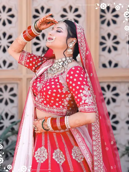 A stunning portrait of the bride in her red and white lehenga, posing gracefully against a traditional backdrop.