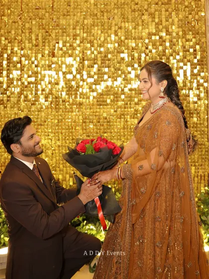 A golden shimmer wall provides a stunning and glamorous backdrop for key moments, like this romantic proposal during an engagement party. It creates a vibrant and celebratory atmosphere perfect for photos.