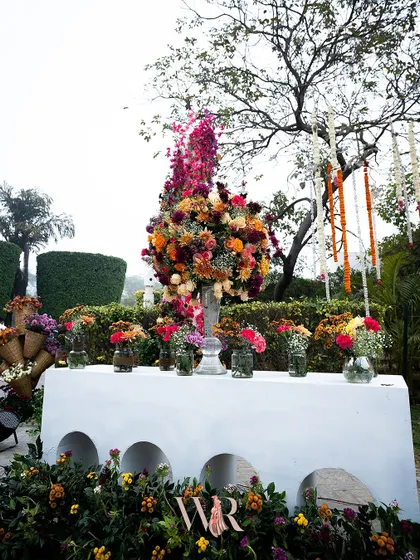 A console table at the entrance, decorated with an abundance of colorful flowers in various vases. The modern white console with its arched details provides a clean contrast to the wildness of the blooms.