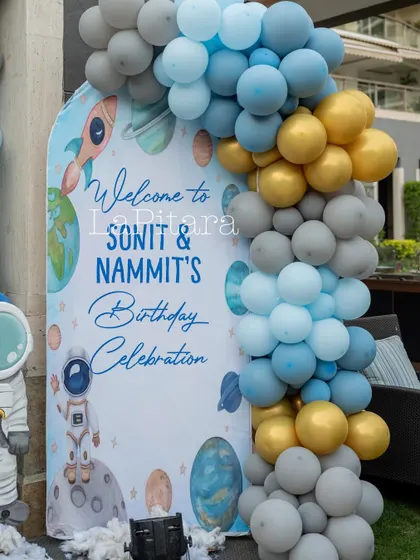 A personalized welcome sign for Sonit and Nammit's birthday celebration, framed by a beautiful balloon garland in blue, grey, and gold.