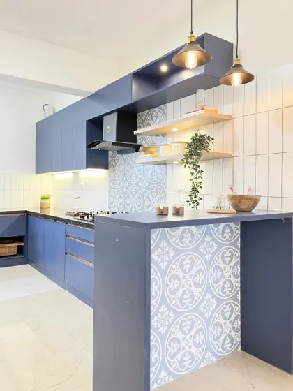 Another view of the blue kitchen, focusing on the breakfast counter and the stylish industrial-style pendant lights that illuminate it.