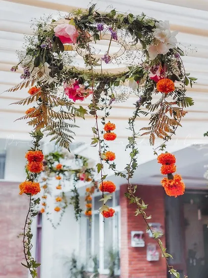 I love adding delicate touches like this minimalistic floral chandelier. Made with marigolds, ferns, and other wildflowers, it added a touch of rustic charm to the Haldi ceremony tent.