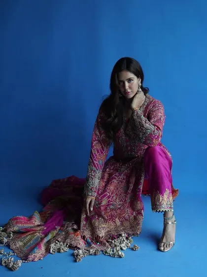 A full seated pose showing how the outfit moves and drapes. The flow of the dupatta and the intricate pants are on full display.