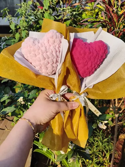 Two of our crochet sweetheart bouquets, one in light pink and one in magenta. These plush hearts are a unique way to show your love.