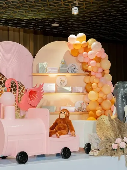 A closer look at the pink safari train and monkey prop from the boho-themed party. These elements add a playful and interactive touch for the children.