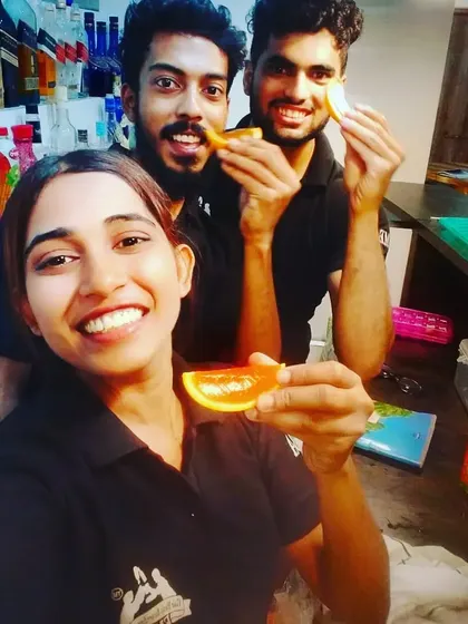 Three students having fun with orange slices after a garnish preparation class.