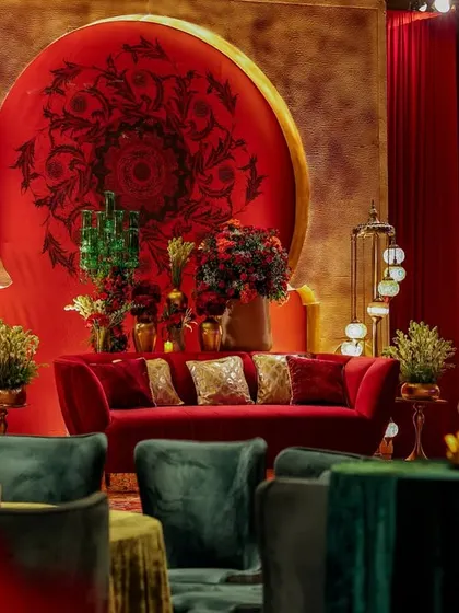 A view of the main seating stage from across the lounge. The composition shows the interplay of different seating arrangements, from round tables to plush sofas, all unified by the rich color palette and design motifs.
