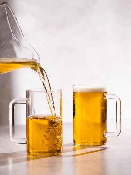 An action shot showing beer being poured into the glass mugs. This dynamic image highlights the product in use and is more engaging than a static shot.