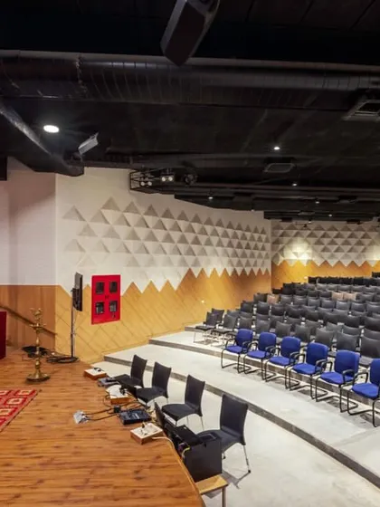 The auditorium at the Sona University Centre, with its distinctive geometric acoustic wall panels. The design creates a visually engaging environment that is tuned for performance, suitable for lectures, cultural events, and conferences.