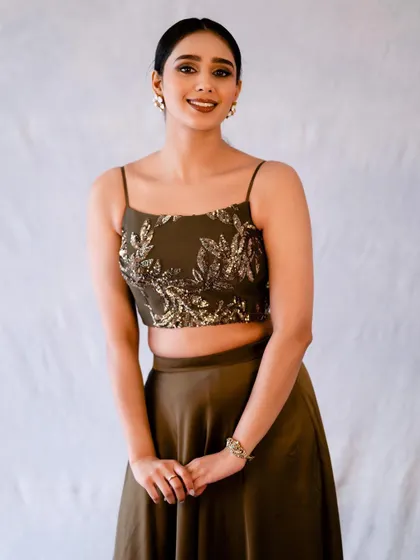 A smiling, happy shot in the olive green outfit. It’s a warm and approachable look that contrasts with the more high-fashion poses.