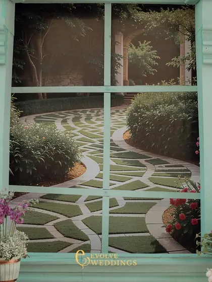 A view through one of the painted windows on the stage backdrop, looking out onto a printed image of a beautiful garden path. This clever design element adds depth and a sense of realism to the set.