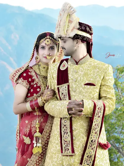A classic pose that showcases the couple's coordinated wedding outfits. The bride's look towards the groom adds a touch of romance.