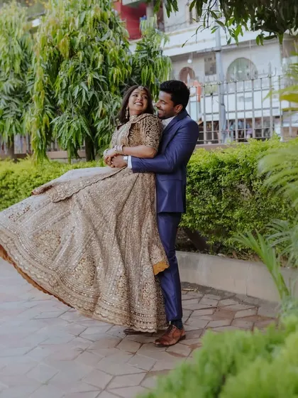 A joyful shot of the groom lifting and spinning his bride, her golden lehenga fanning out beautifully.