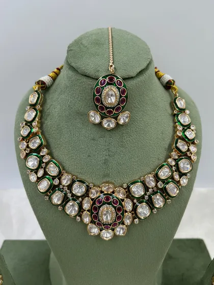 A pair of stunning oversized earrings with green and red Meenakari work, set with Moissanite stones. These are perfect as standalone statement pieces.