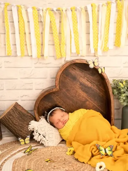 Another angle from the sunny sunflower session, showing the baby lying beside a heart-shaped prop, creating a scene full of warmth and happiness.