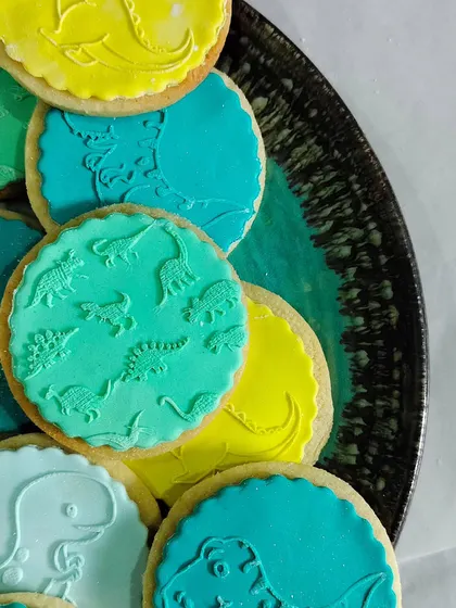 A platter of colorful dinosaur cookies, all decorated using our easy-to-use fondant stamps.